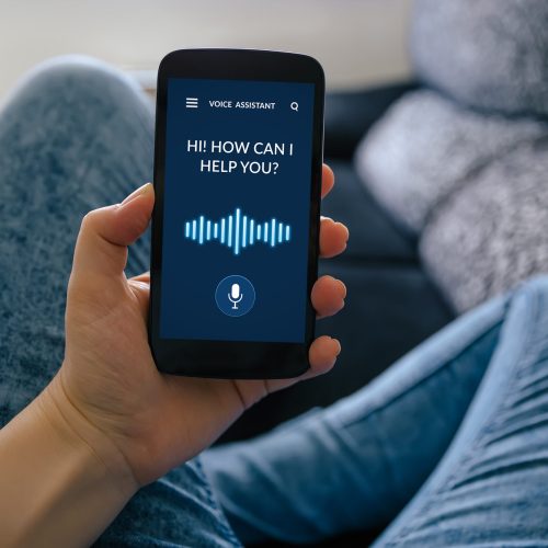 A person using a cell phone with a voice assistant to aid in digital inclusivity.